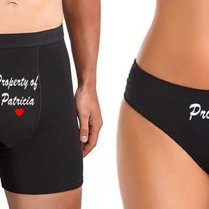 May include: A black boxer brief with the text "Property of Patricia" and a red heart. A black thong with the text "Property of Theo" and a red heart.