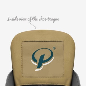 May include: Inside view of a shoe tongue with a tan leather surface and a square patch with a teal blue and white logo of a stylized letter "P" with a registered trademark symbol.