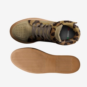 May include: A pair of high-top sneakers with a brown and tan leopard print upper, a brown leather toe, and a brown rubber sole. The sneakers have a lace-up closure and a padded tongue.