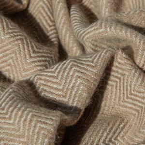 Plaid dalle tonalità calde del beige in puro cachemire per aggiungere un tocco di stile alla tua casa. Coperta da sofà che amerai per anni