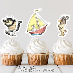 Op de afbeelding: Drie cupcakes versierd met Where the Wild Things Are-thema toppers. De toppers bevatten een gele zeilboot met een figuur in een rood-wit gestreept shirt, een harige monster met zwarte ogen en een gestreept lichaam, en een vogelachtig wezen met een gele snavel en bruine veren.