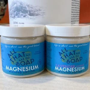 May include: Two white jars of whipped magnesium lotion with blue labels. The labels say "All That Bar of Soap" and feature the words "Magnesium" and "Lavender Scented Magnesium".