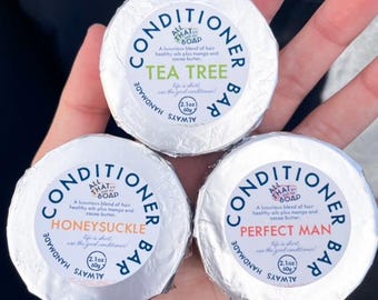 May include: Three silver-wrapped conditioner bars with blue and white labels. The labels read "All That Soap Conditioner Bar" with different scents: Tea Tree, Honeysuckle, and Perfect Man. Each bar is 2.1 oz (60g).