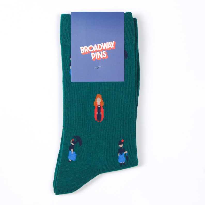 May include: Green socks with a white tag that says "Broadway Pins". The socks have a pattern of women in different outfits.