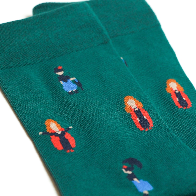 May include: A pair of green socks with a repeating pattern of women in different outfits. The women are wearing red, blue, and black clothing.