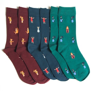 May include: Four pairs of socks with different colored backgrounds and a repeating pattern of a woman dancing. The socks are burgundy, dark blue, light blue, and green.
