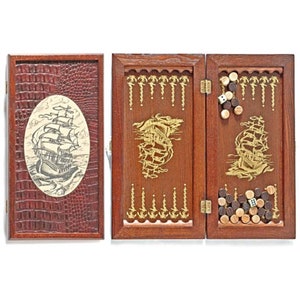 Könnte beinhalten: Ein Backgammon-Set aus Holz mit dunkelbraunem, krokodiltexturiertem Äußeren. Das Set zeigt eine detaillierte Schiffsillustration und goldfarbene Akzente. Enthält Holzspielsteine und Würfel.