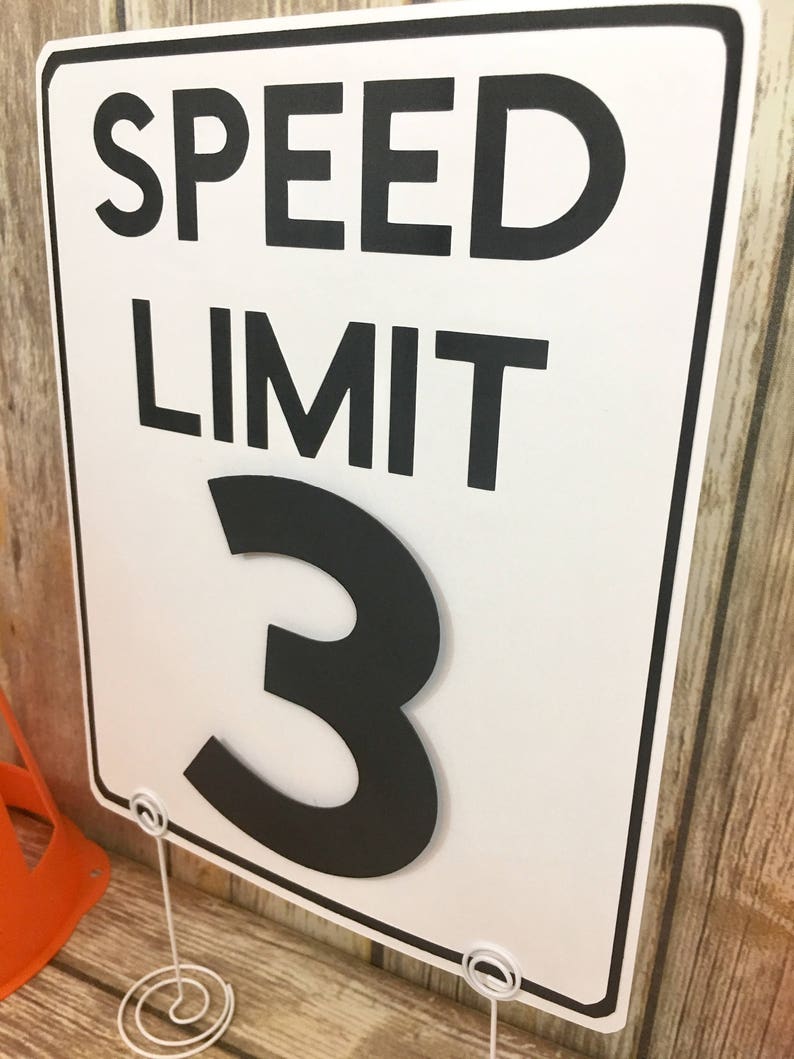 May include: White speed limit sign with black text and border. The sign reads "SPEED LIMIT 3".