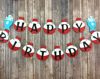 May include: A red and white fishing bobber banner that says "Happy Birthday" with blue fish on each end.