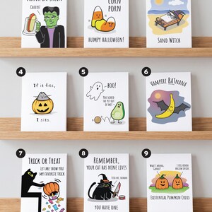 May include: A collection of nine white greeting cards featuring Halloween-themed illustrations and puns. Designs include Frankenstein with a beer, candy corn, a witch on a beach, a cat in a pumpkin, a ghost and avocado, a banana bat, a cat, and pumpkins.