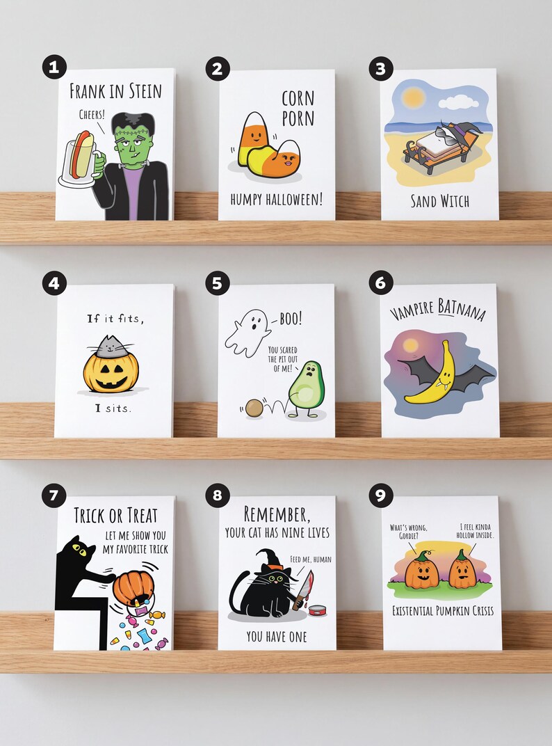 May include: A collection of nine white greeting cards featuring Halloween-themed illustrations and puns. Designs include Frankenstein with a beer, candy corn, a witch on a beach, a cat in a pumpkin, a ghost and avocado, a banana bat, a cat, and pumpkins.