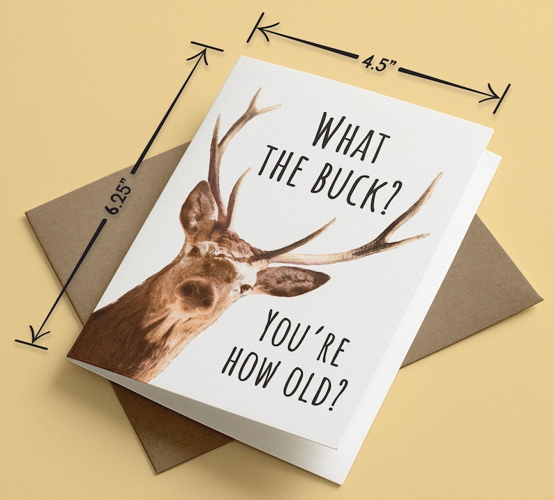 May include: A white greeting card featuring a brown deer with antlers and the black text WHAT THE BUCK? YOU'RE HOW OLD? The card measures 4.5 inches by 6.25 inches and is placed on top of a brown envelope.