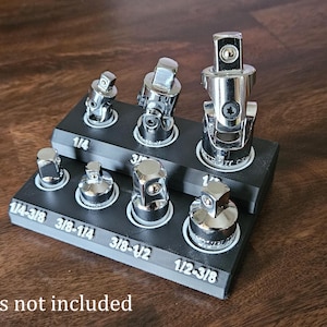 May include: A black plastic organizer with 8 slots for storing socket adapters. The organizer has white labels with the following sizes: 1/4, 3/8, 1/2, 1/4-3/8, 3/8-1/4, 3/8-1/2, 1/2-3/8. The text "*Tools not included" is printed below the organizer.