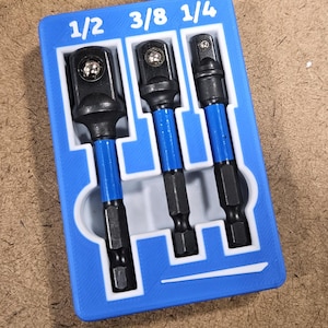 May include: A blue 3D-printed tool holder with three black and blue socket adapters labeled 1/2, 3/8, and 1/4. The text "TOOLS NOT INCLUDED" is at the bottom. The tools are arranged in a white-lined tray.