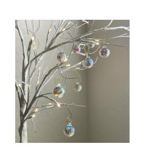 May include: A white twig tree decorated with iridescent glass ornaments. The ornaments are hanging from gold wire hooks.