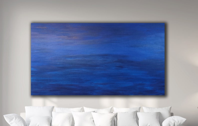 May include: A large, rectangular abstract painting with a predominantly blue color palette. The artwork features horizontal brushstrokes in varying shades of blue, creating a sense of depth and movement. The painting is mounted on a wall above white pillows.
