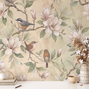Può includere: Carta da parati floreale ad acquerello con fiori di magnolia e uccelli canori in tenui colori pastello. Il design include rami con foglie e boccioli, creando un'estetica naturale ed elegante. Lo sfondo ha un effetto sottile e strutturato.