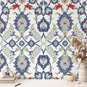 Op de afbeelding: Een herhalend patroon met gestileerde bloemen- en bladmotieven in blauw, rood en groen op een witte achtergrond. Het ontwerp bevat symmetrische arrangementen van bloemen en bladeren, geschikt voor behang of stof.
