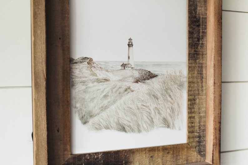 May include: A framed watercolor painting of a lighthouse on a grassy cliff overlooking the ocean. The lighthouse is white with a black roof and a small window. The grass is a light green color and the ocean is a light blue color.