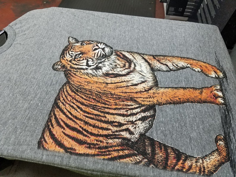 May include: A gray t-shirt with a black and orange tiger illustration printed on the front.