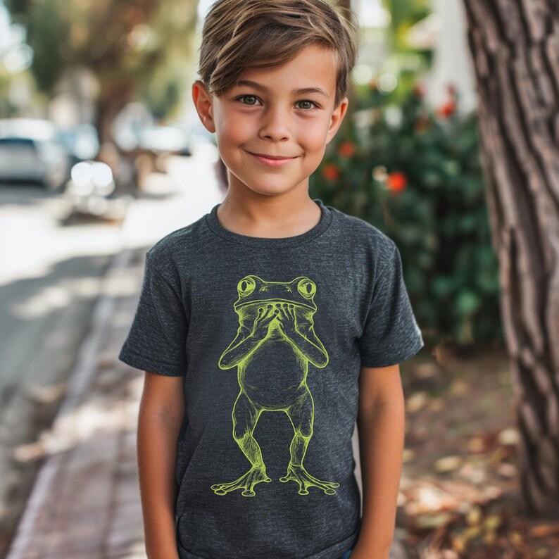 May include: A dark gray t-shirt with a lime green illustration of a frog covering its eyes with its hands.