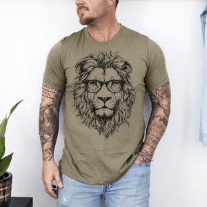 May include: A green t-shirt featuring a black and white illustration of a lion wearing glasses.