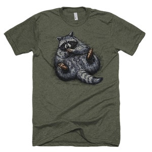 May include: A green t-shirt with a graphic of a raccoon curled up in a ball. The raccoon is gray and black with a white stripe on its face.