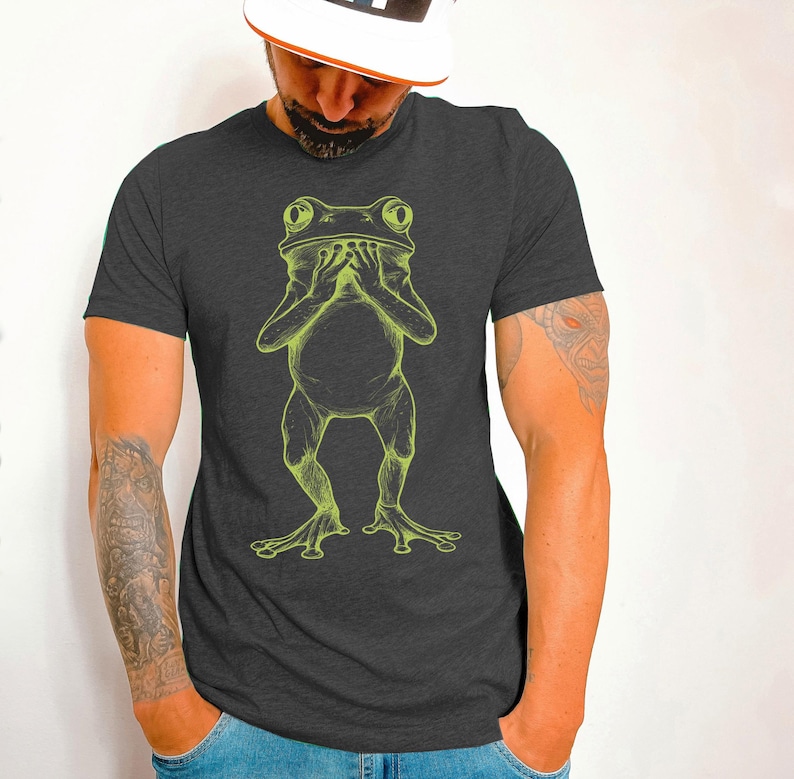 May include: A dark gray t-shirt with a green line drawing of a frog covering its mouth with its hands.