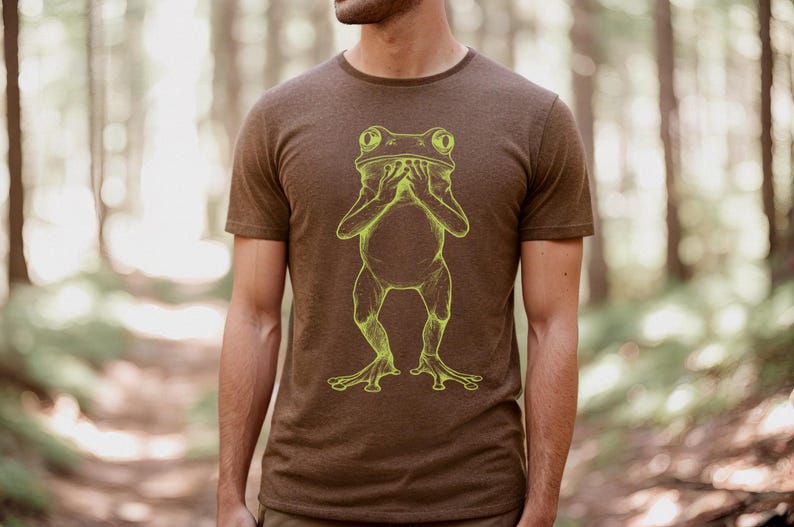 May include: A brown t-shirt with a yellow outline of a frog covering its eyes with its hands.