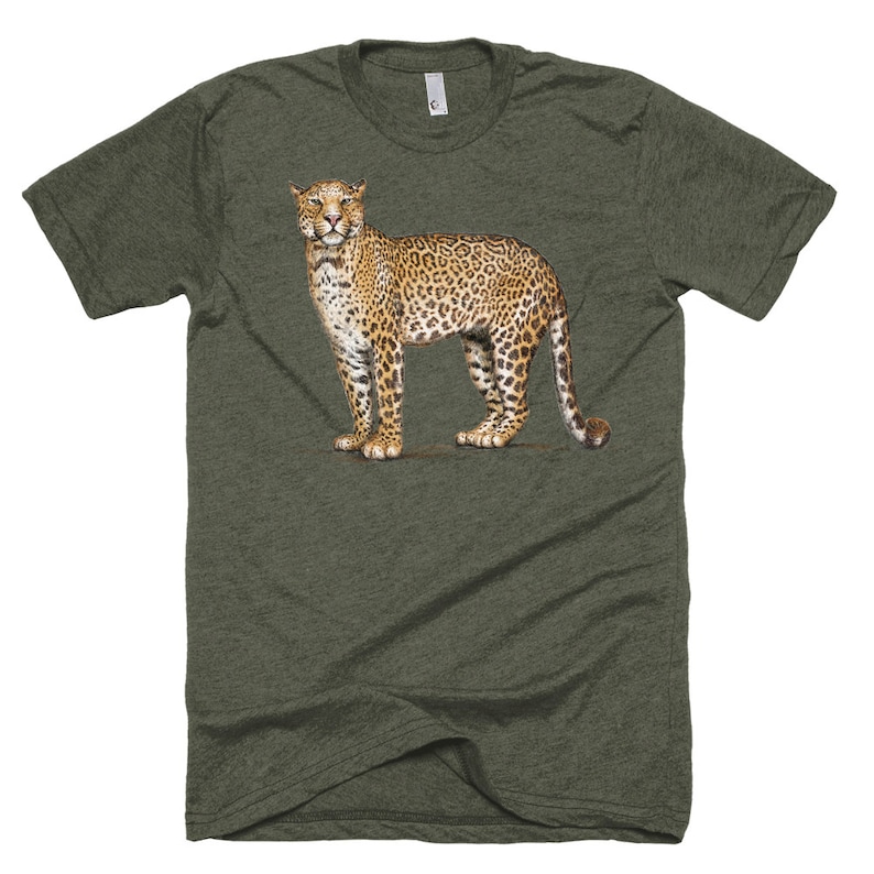 Puede incluir: Una camiseta verde con una ilustraci&oacute;n detallada de un jaguar. El jaguar se muestra de pie, mostrando su distintivo pelaje manchado en tonos marrones y beige. La camiseta tiene cuello redondo y mangas cortas.
