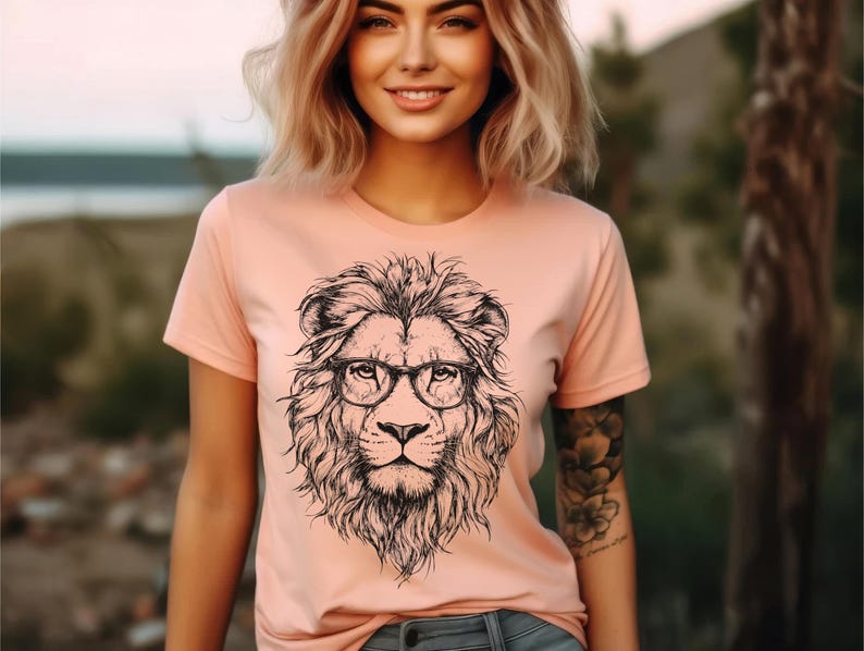 May include: A peach-coloured t-shirt with a black and white illustration of a lion wearing glasses.