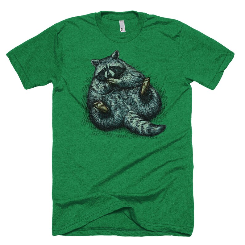 May include: A green t-shirt with a graphic of a raccoon curled up in a ball. The raccoon is drawn in a realistic style with detailed fur and a black mask.