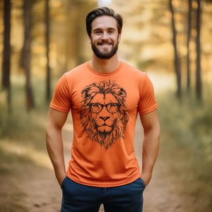 May include: A man wearing an orange t-shirt with a black and white illustration of a lion wearing glasses. The lion is the centrepiece of the design.