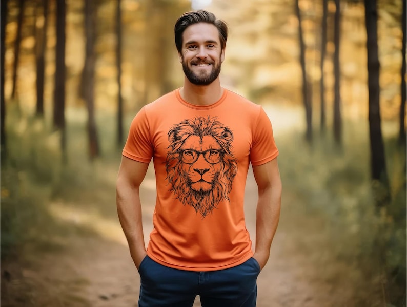 May include: A man wearing an orange t-shirt with a black and white illustration of a lion wearing glasses. The lion is the centrepiece of the design.