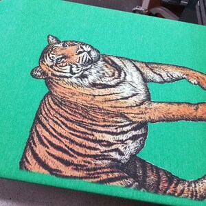 May include: A green t-shirt with a black and orange tiger illustration printed on the front.