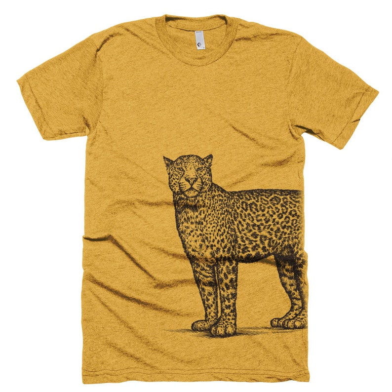 May include: A mustard yellow t-shirt with a black and white illustration of a leopard on the right side of the shirt.