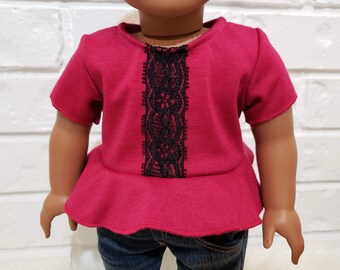 Peut inclure: Une chemise de poupée rouge avec une bordure en dentelle noire sur le devant. La chemise a un ourlet à volants et des manches courtes.