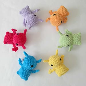 May include: Six crocheted plush toys shaped like ants in different colours: purple, red, green, yellow, orange, and blue.