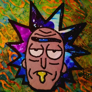 Puede incluir: Parche bordado con la cara de un personaje de dibujos animados con un diseño puntiagudo en forma de estrella alrededor de la cabeza. El personaje tiene una cara marrón claro, ojos blancos y baba amarilla. El fondo es un patrón abstracto colorido.