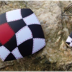May include: Two polymer clay earrings with a black and white checkered pattern and red diamond accents. The earrings are shaped like squares and have a stitched design.