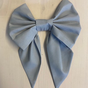 May include: A large, light grey fabric bow with pointed ends.