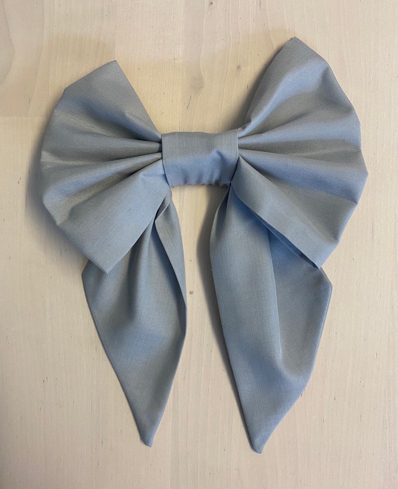 May include: A large, light grey fabric bow with pointed ends.