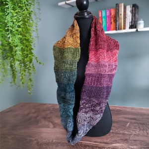 Pode incluir: Uma echarpe de malha infinita colorida com um degradê de cores do amarelo ao roxo. A echarpe é feita de fio macio e é perfeita para se manter aquecido no inverno.