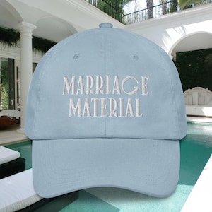 May include: A light blue baseball cap with white embroidery that reads "Marriage Material".