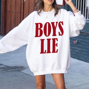 May include: White sweatshirt with the phrase "BOYS LIE" printed in red.