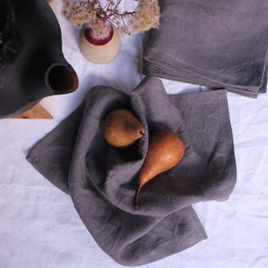 May include: Two brown pears on a gray linen napkin. The napkin is folded and the pears are partially visible.