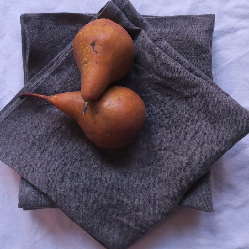 May include: Two brown pears on a stack of gray linen napkins.