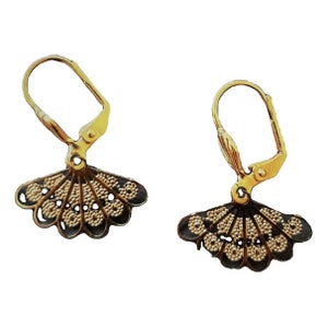 May include: A pair of gold earrings with a black and gold fan-shaped design. The earrings have a hook closure.