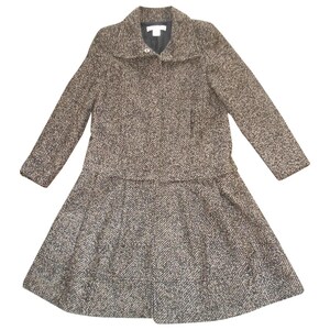 May include: A brown and black tweed coat with a long, A-line silhouette. The coat has a collar, a zipper closure, and long sleeves.