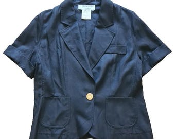 Op de afbeelding: Een donkerblauwe blazer met korte mouwen, een enkele gouden knoop en twee zakken. Het label "Yves Saint Laurent" is zichtbaar aan de binnenkant van de kraag.